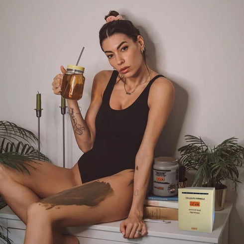 Woman relaxing with a drink while GUAM seaweed mud wrap works on her legs