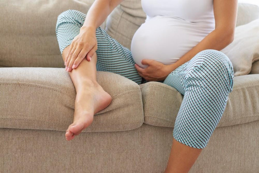 Pregnant woman on the sofa touching her leg, cellulite on legs during pregnancy