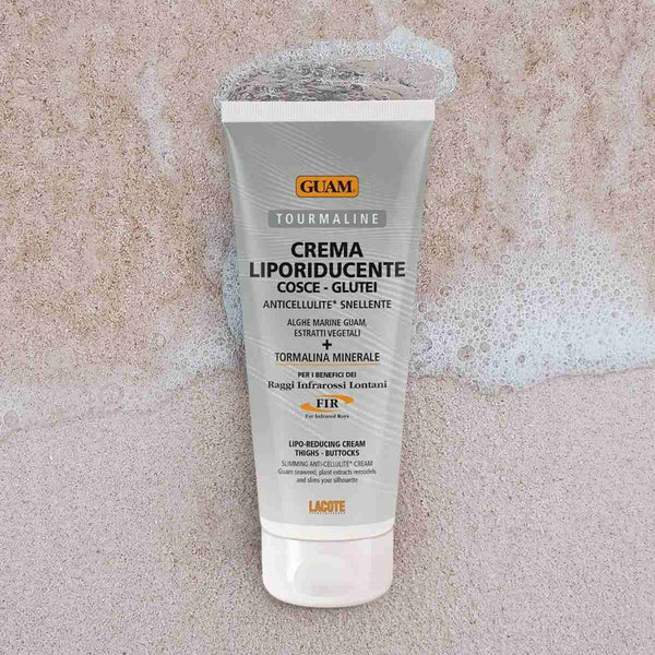 GUAM Extra Slimming Lipo Cream tube on sand for stubborn thigh fat after weight loss