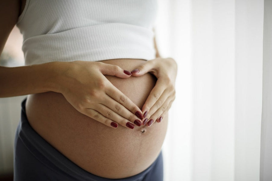 Pregnant woman holding her belly, the right time to start using stretch mark cream during pregnancy
