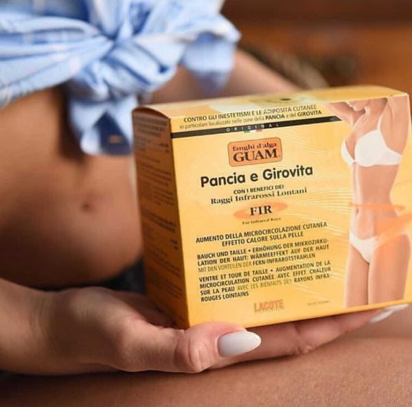 Hands holding the GUAM Tummy Tightening Stomach Wrap box against the belly
