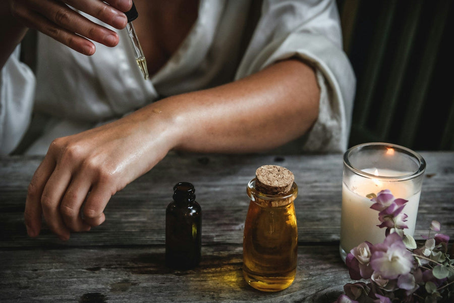Hands mixing essential oils with a carrier oil for safe skin tightening blends