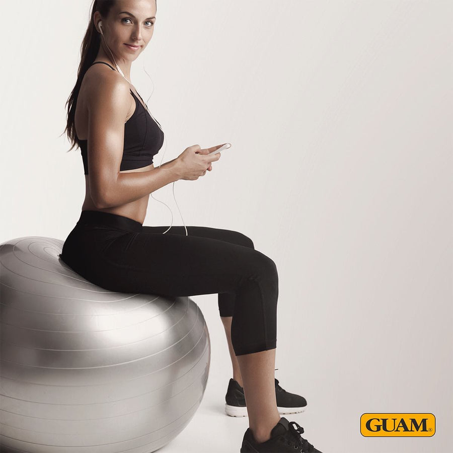 Woman exercising on a gym ball in black GUAM anti-cellulite capri leggings