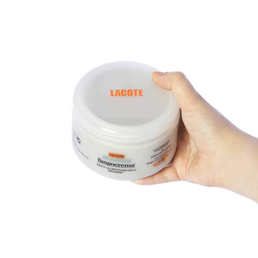 Hand holding a jar of GUAM Fangocrema Tourmaline infrared anti-cellulite cream