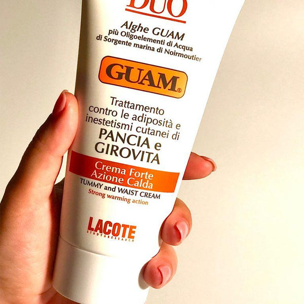 Hand holding GUAM Duo Slimming Tummy Cream for stomach skin tightening after weight loss