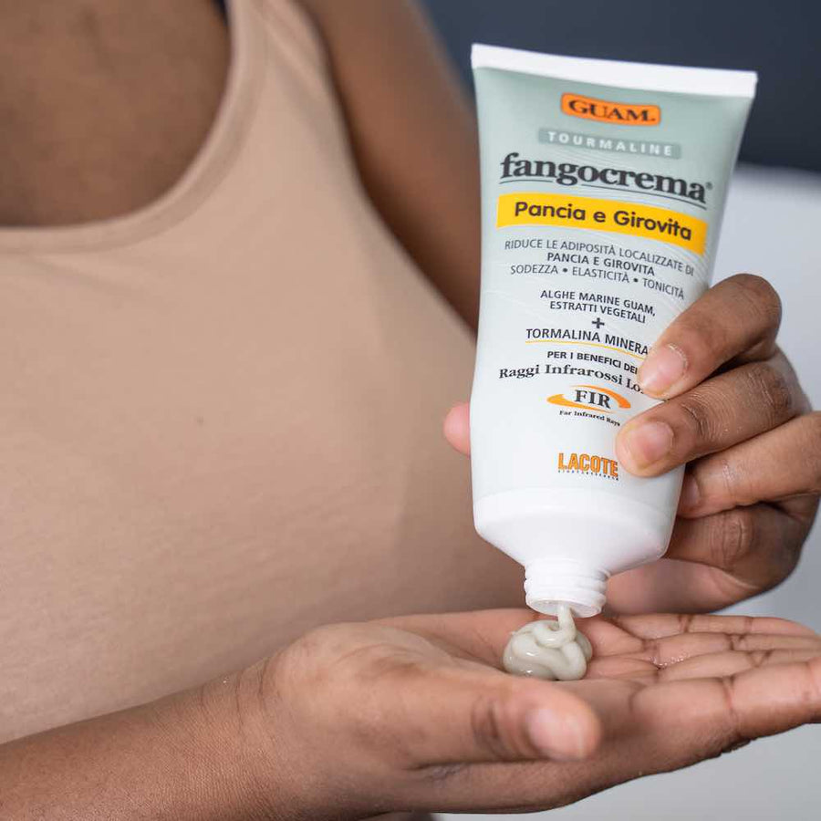 Squeezing GUAM Fangocrema cellulite cream into the palm before massaging it into the legs