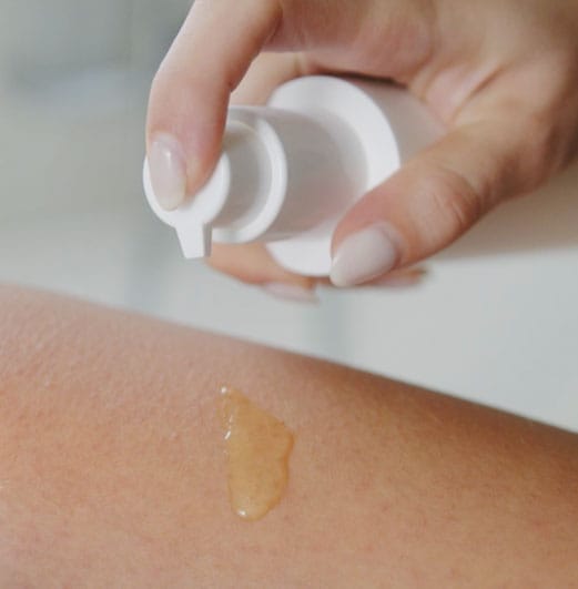 Body oil pumped onto the arm, essential oils for crepey skin on arms and legs